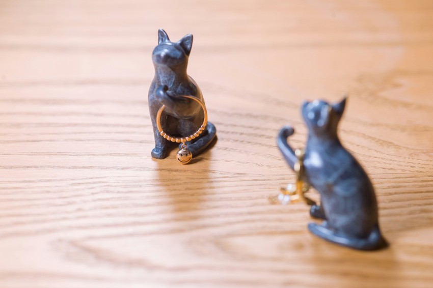 a cat figurine sitting on a table next to a dog figurine