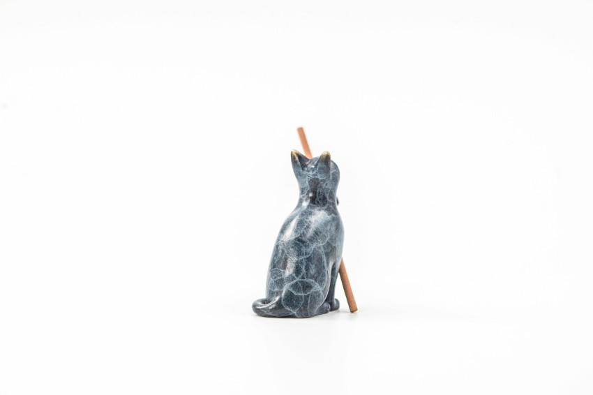 a cat figurine with a wooden stick sticking out of its mouth