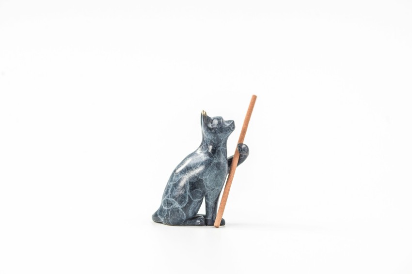 a cat figurine holding a stick on a white background