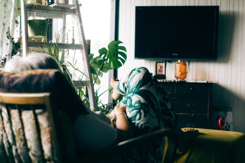 woman sitting on armchair staring at turned off tv