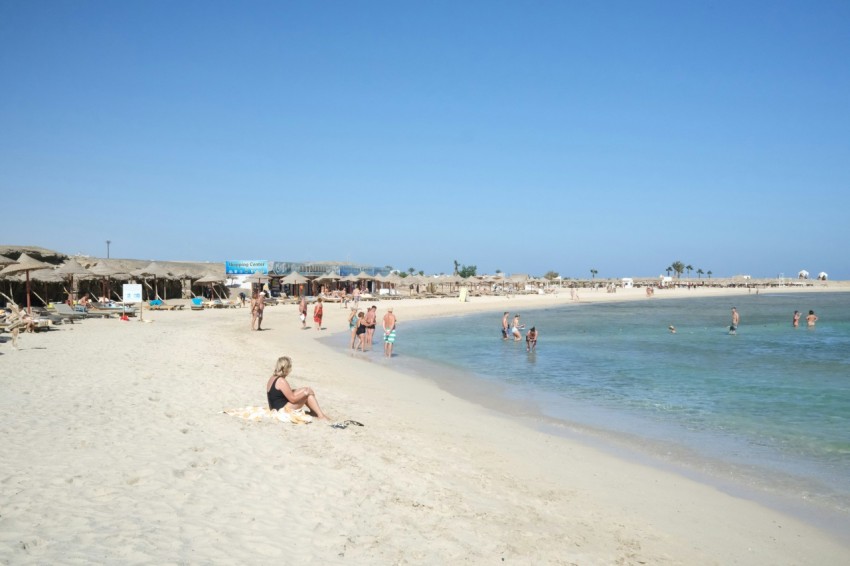 a group of people sitting on top of a sandy beach