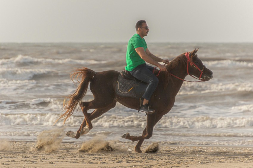 a man riding a horse on the beach VsLhaM