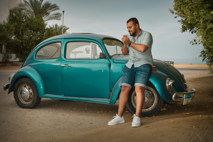 a man sitting on the hood of a blue car