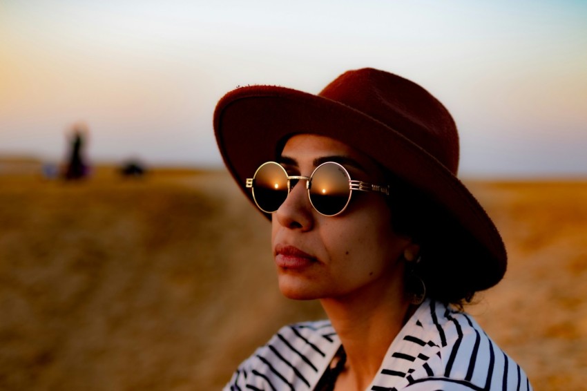 a woman wearing a hat and sunglasses in the desert