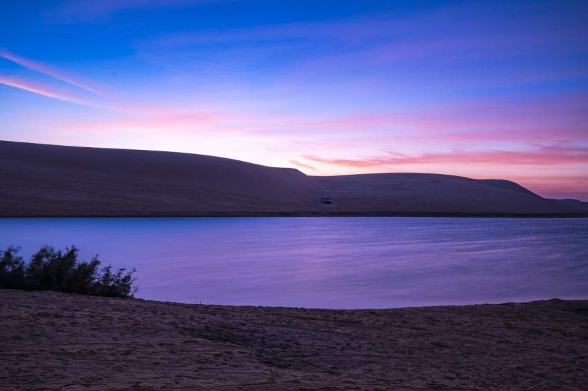 a body of water sitting under a purple sky