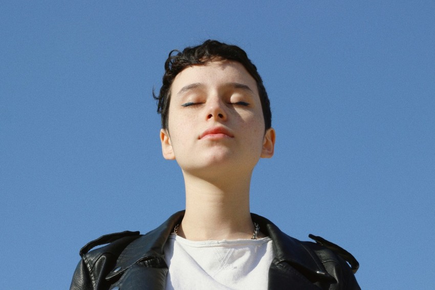 a boy in a leather jacket looking up into the sky