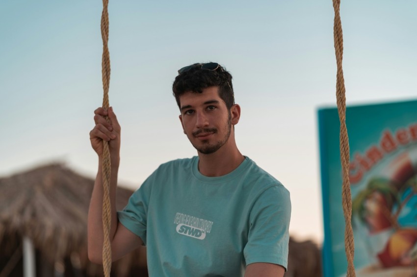 man in teal crew neck t shirt holding brown rope