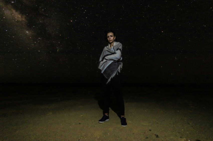 a woman standing in the middle of a field at night