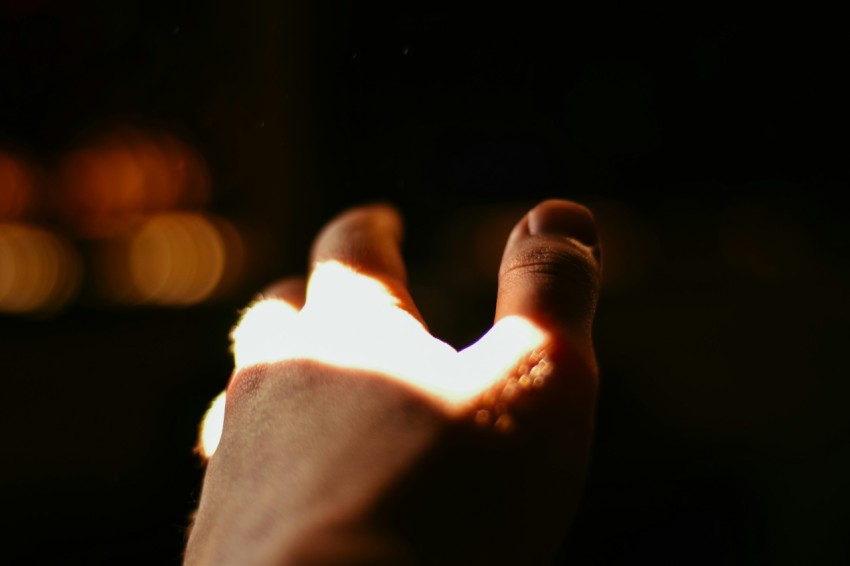 a persons hand holding a lit object in the dark