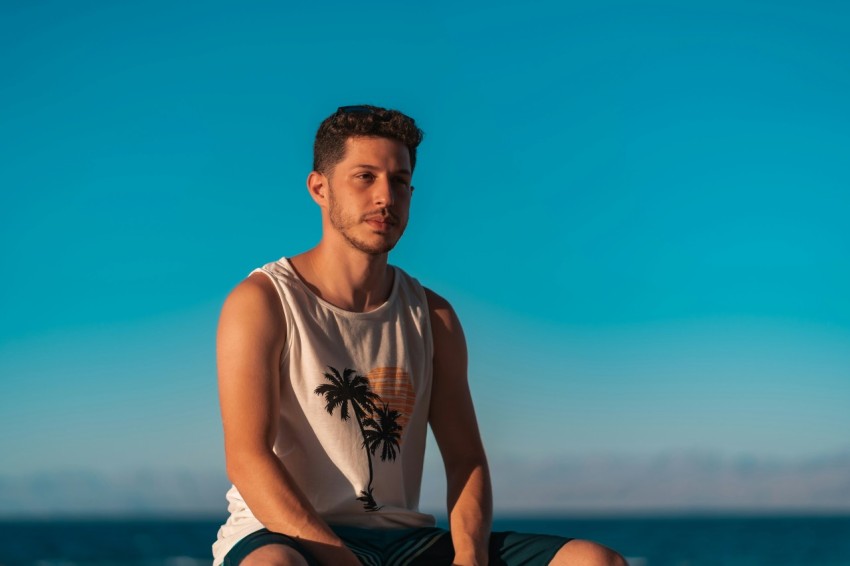 man in white tank top sitting on orange textile