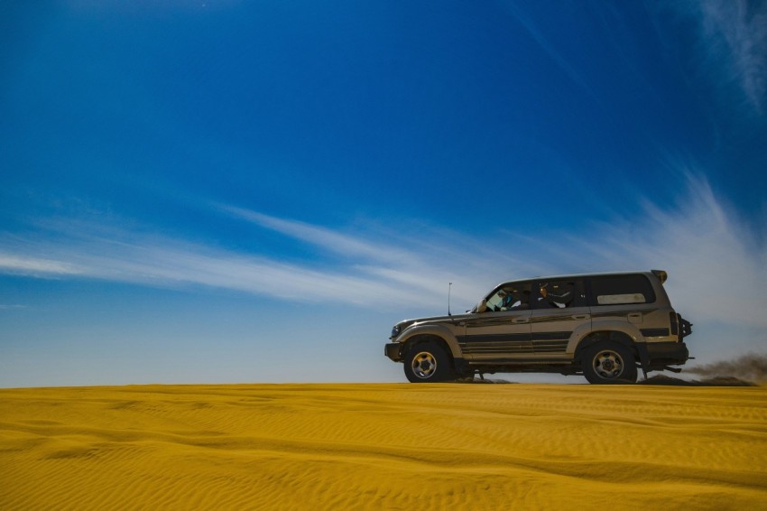 a jeep driving through the desert on a sunny day