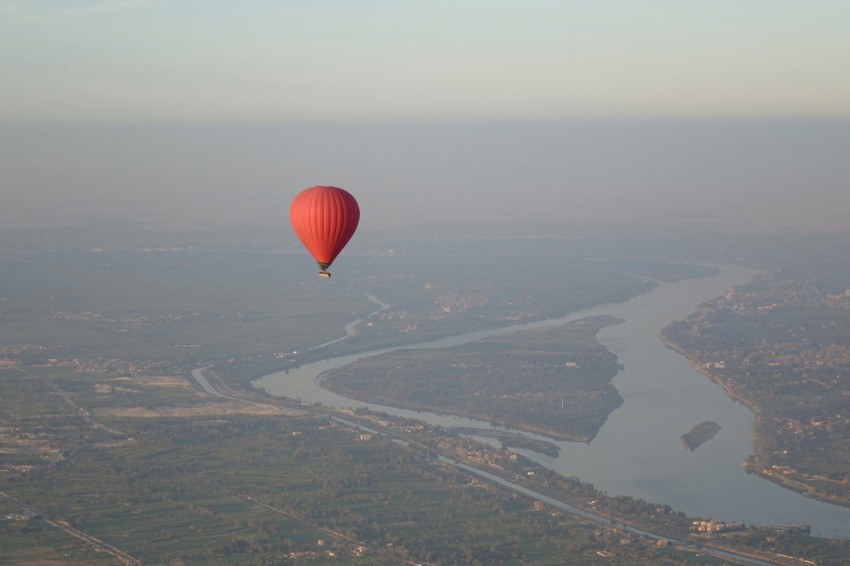 a hot air balloon flying over a river