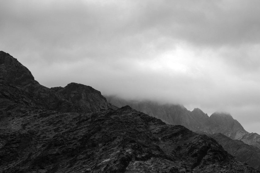 grayscale photo of mountains under cloudy sky