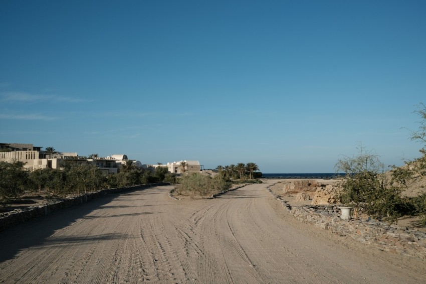 a dirt road with a few buildings in the distance