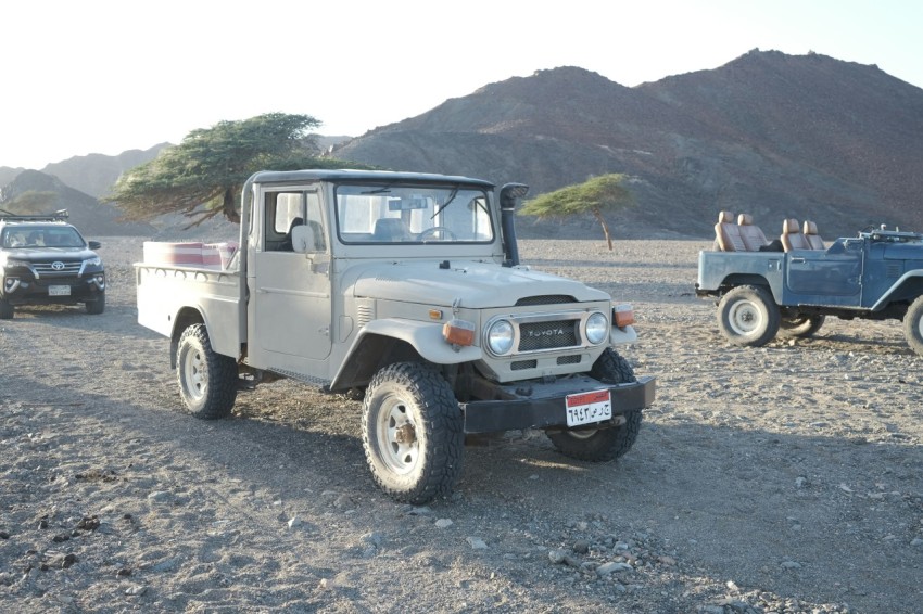 a couple of jeeps that are parked in the dirt