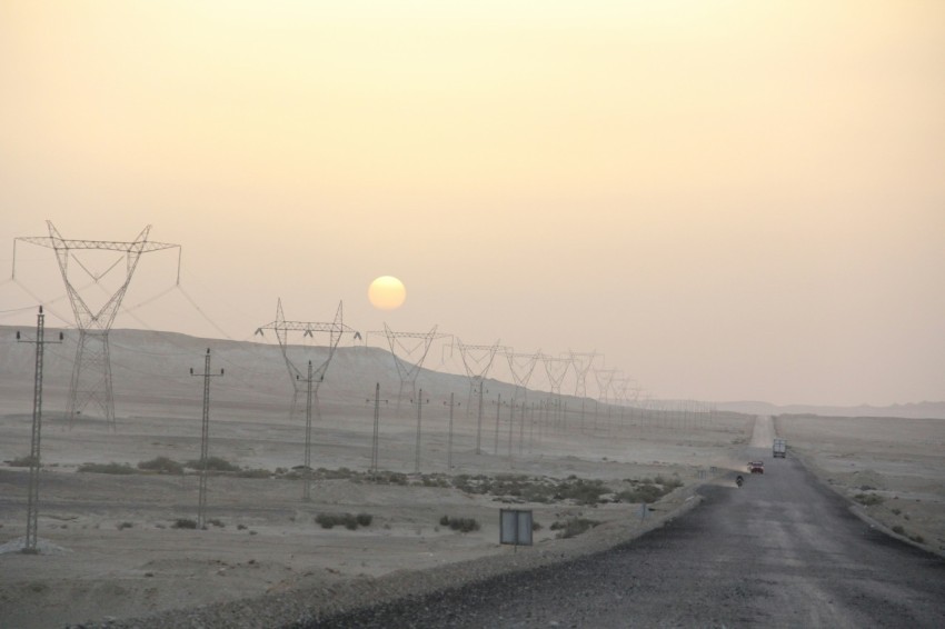 the sun is setting over a road in the desert