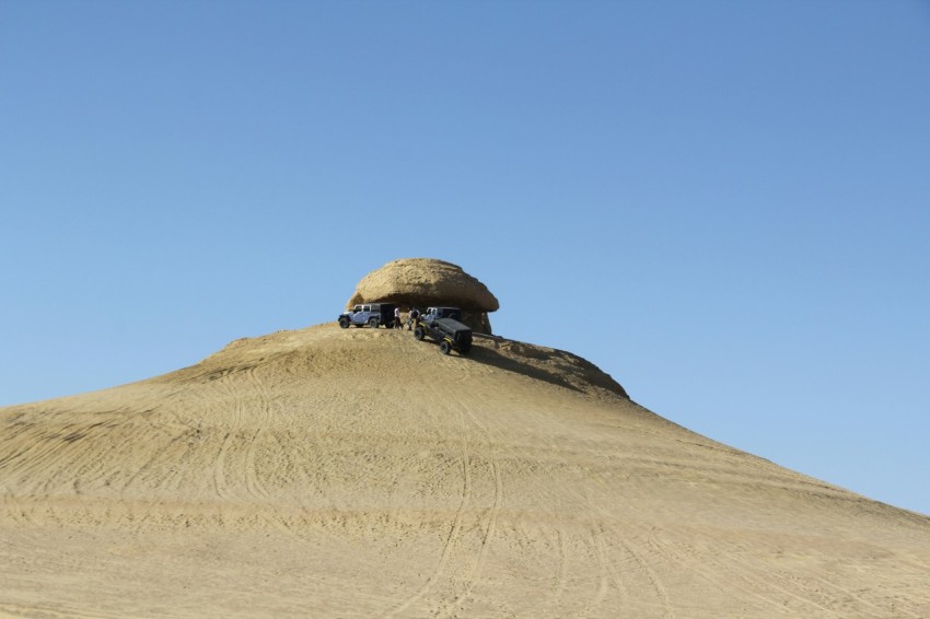 a large rock sitting on top of a sandy hill