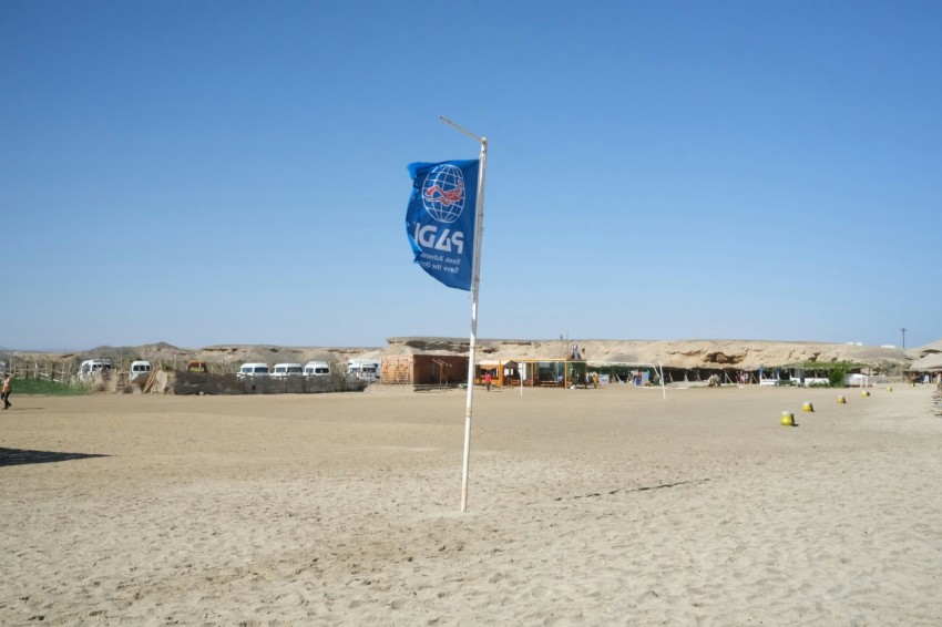 a flag on a pole in the middle of a sandy area