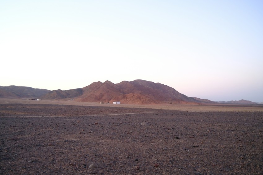 a dirt field with a mountain in the background