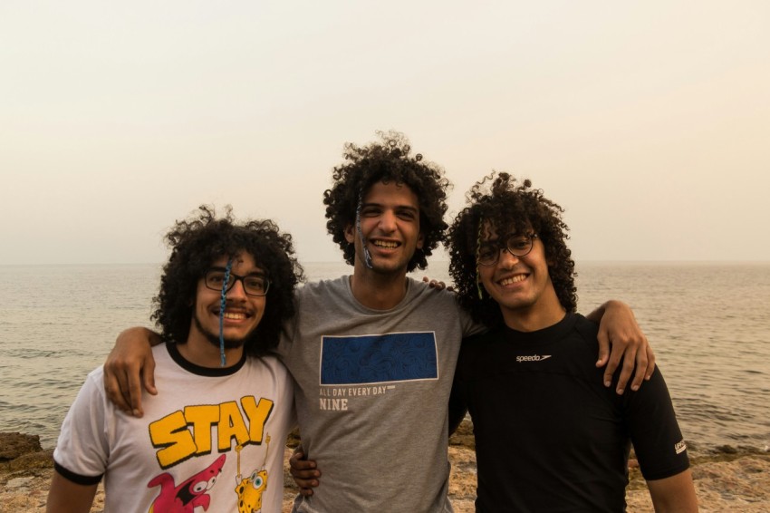 a group of men posing for a picture on a beach