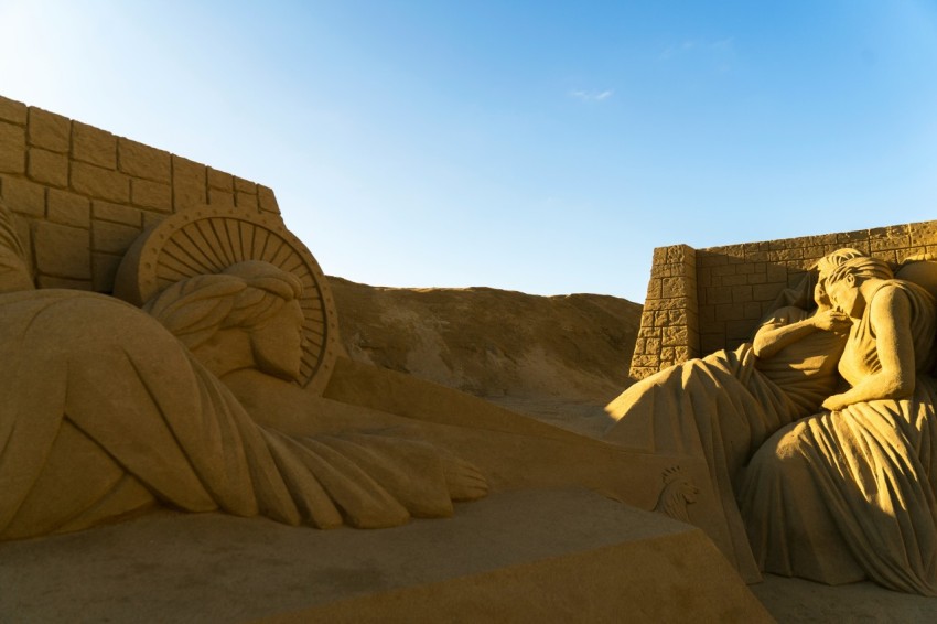 a sand sculpture of a woman laying on a beach