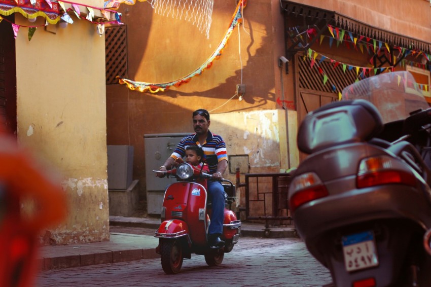 woman in black jacket riding red motor scooter