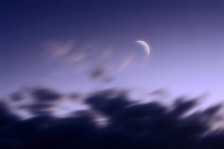 the moon is seen through the clouds in the sky