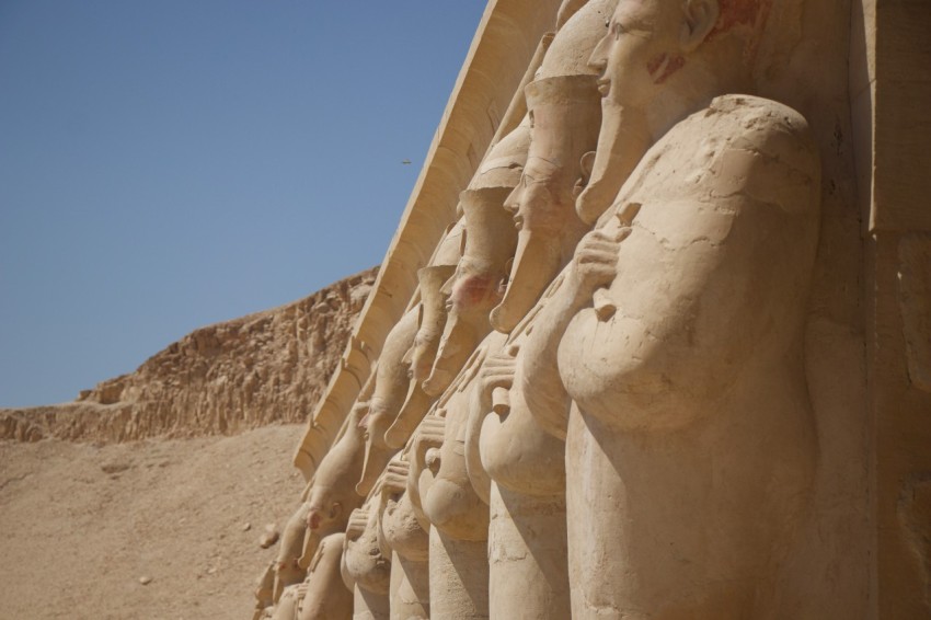 a row of statues in front of a pyramid lmI1572