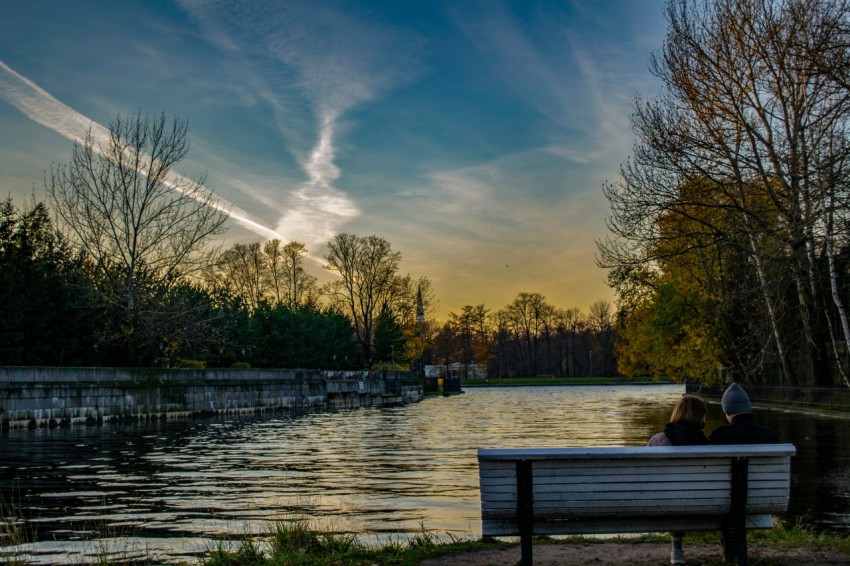 two people sitting on a bench near a body of water