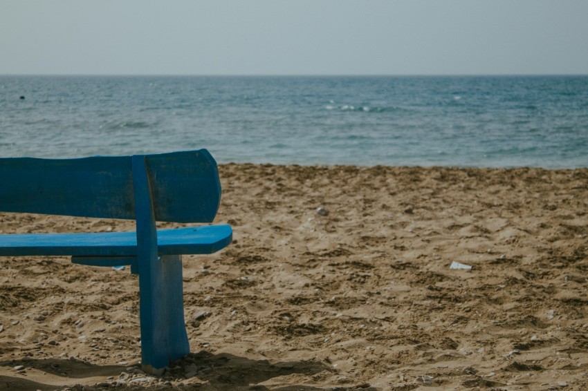 a blue bench on a beach