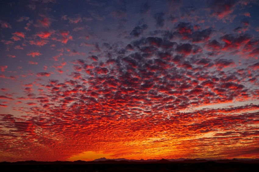 a red and blue sunset with clouds in the sky