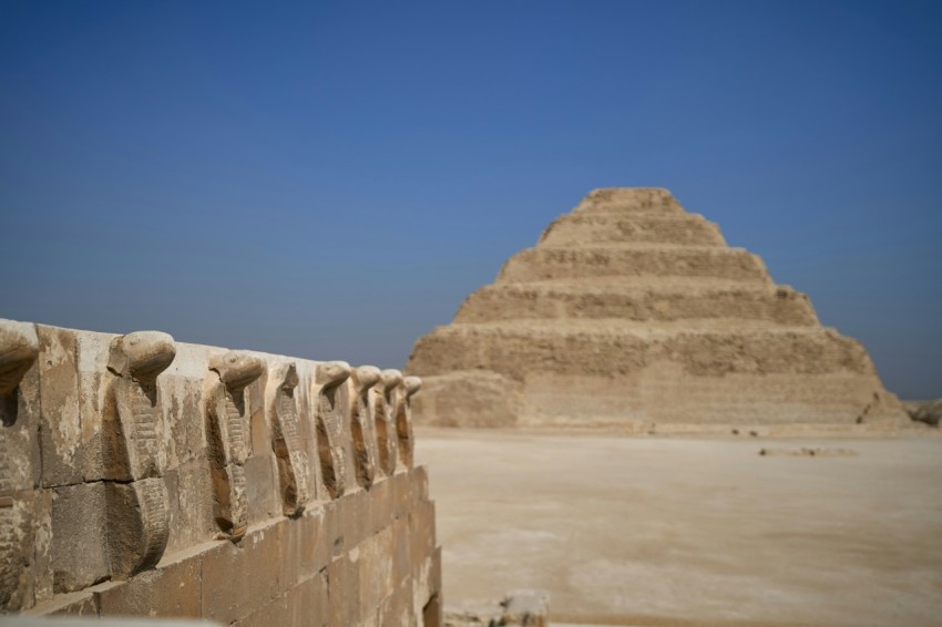 a stone wall with a pyramid in the background KF