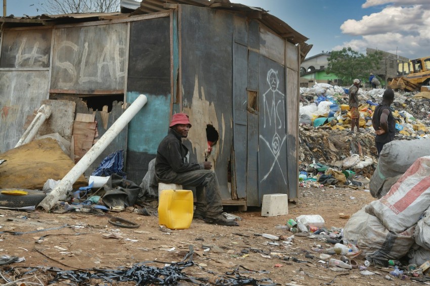 man in black jacket sitting on ground near garbage