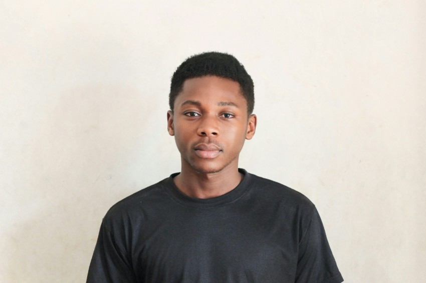 a young man in a black t shirt poses for a picture