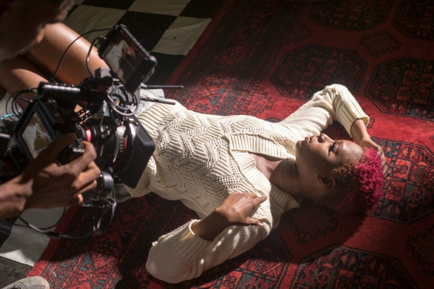 baby in white onesie lying on floor