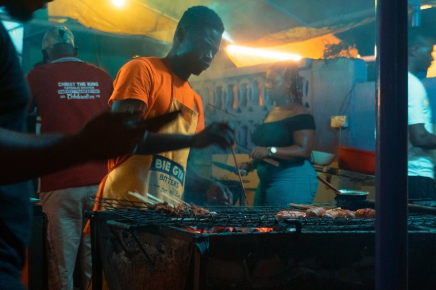 man holds stick towards griller