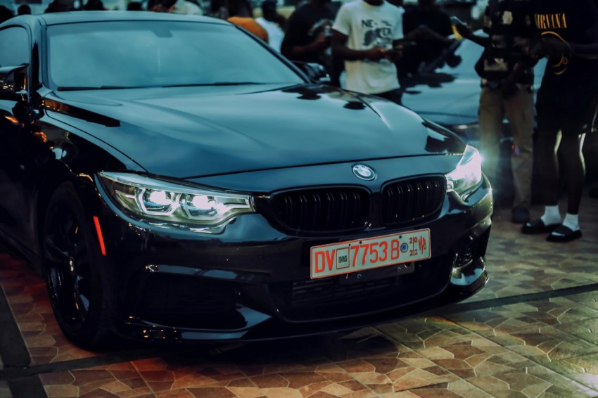 a black car parked in front of a crowd of people