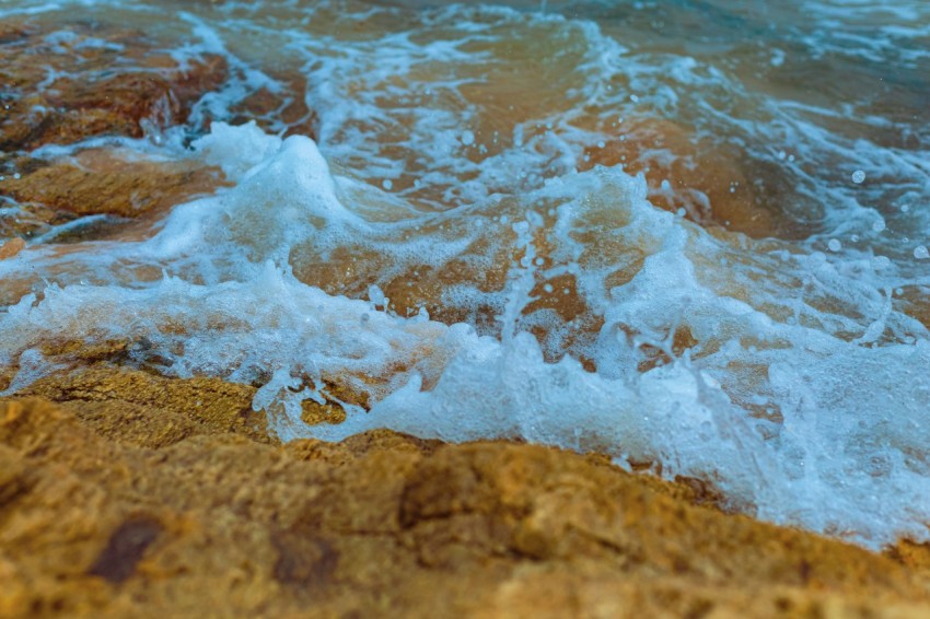 a close up of a wave on a rocky beach WBo18Es