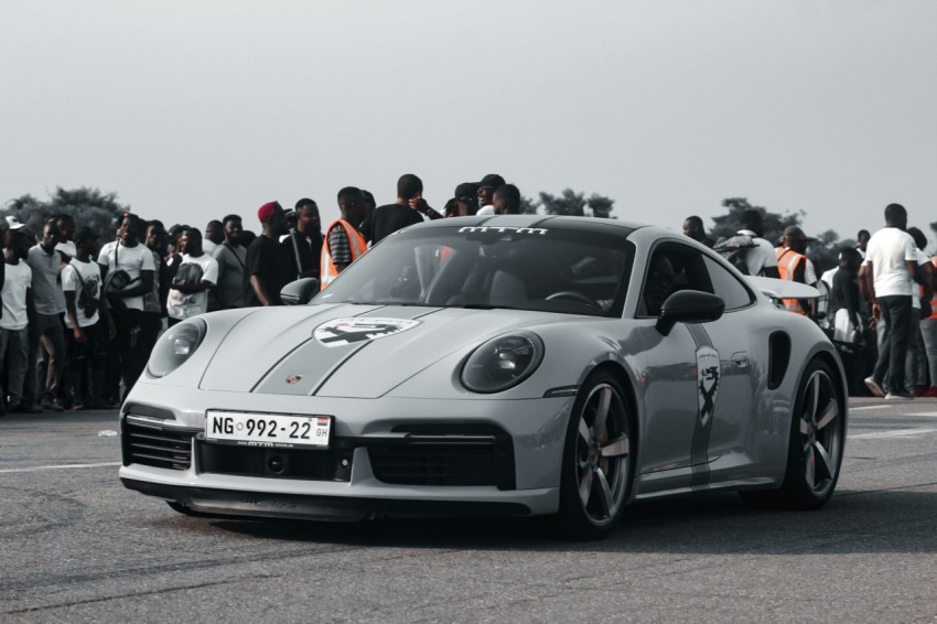 a silver sports car driving past a crowd of people