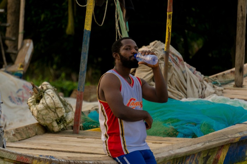 man in white tank top drinking water from bottle
