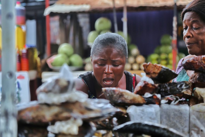 a woman and a child looking at food at a market