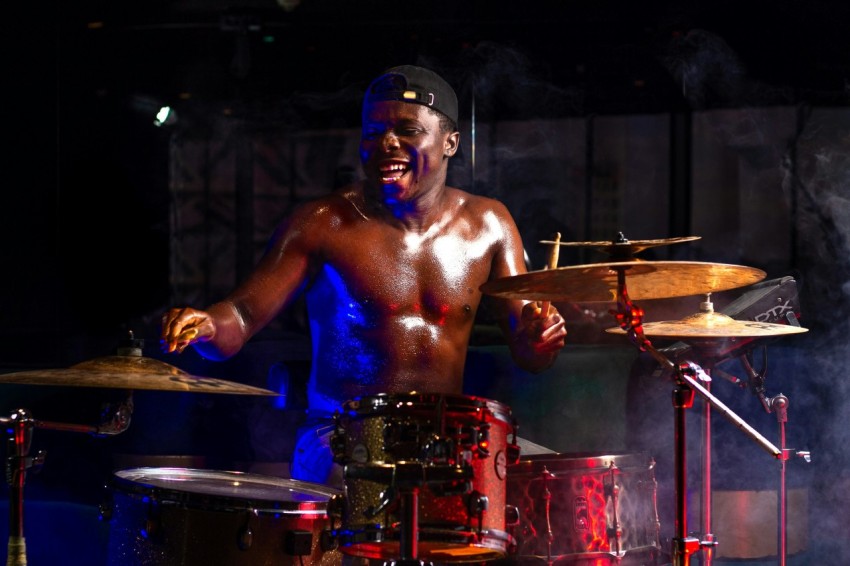 as shirtless guy playing a drum set