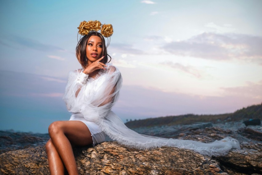 a woman in a white dress sitting on a rock