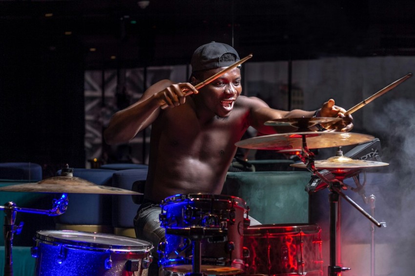 a shirtless man playing drums on stage DweGA