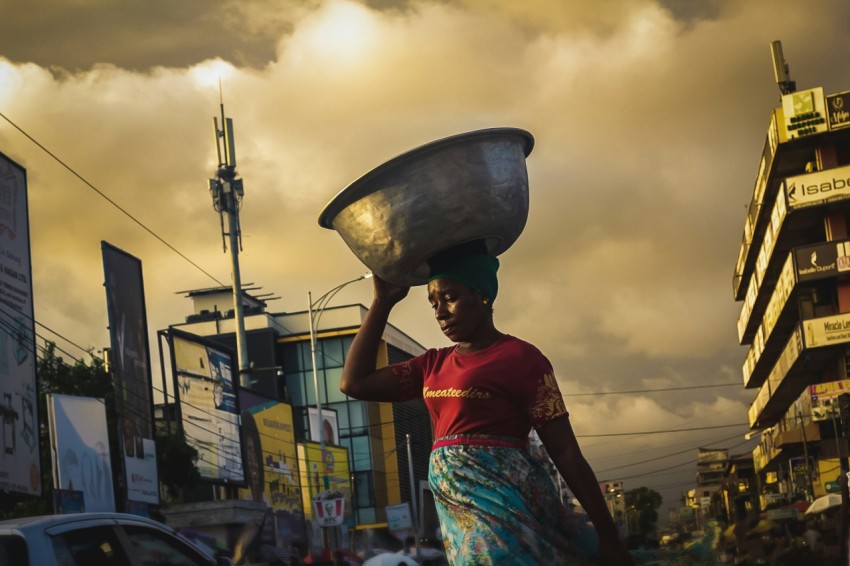 a woman carrying a large metal bowl on her head