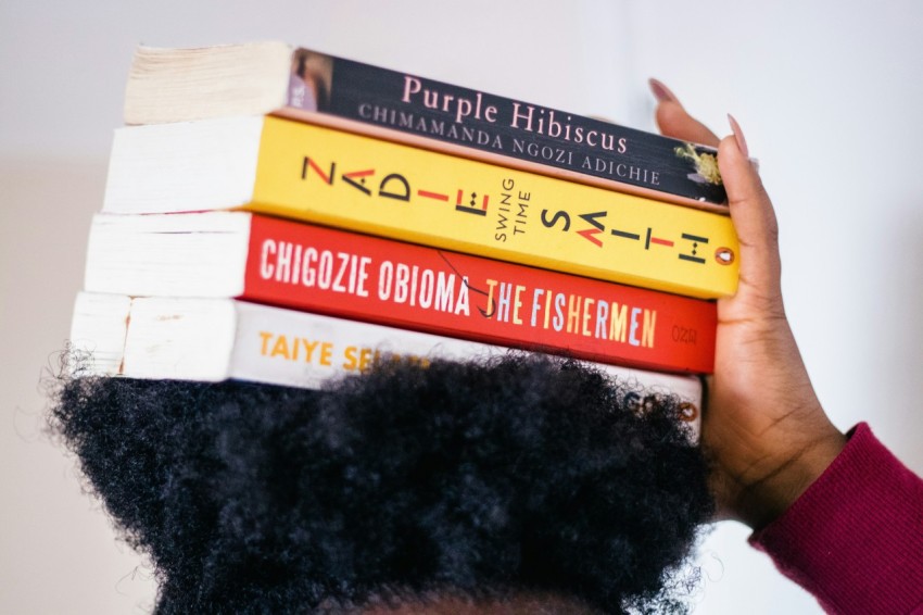 person carrying four assorted title books on head