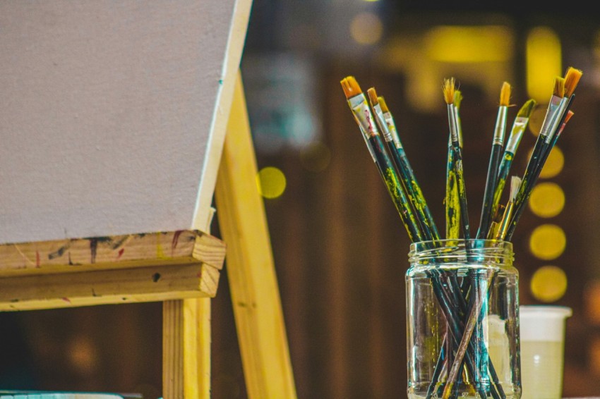 a group of brushes sit in a glass cup