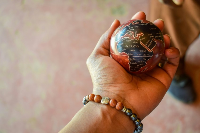 a person holding a small globe in their hand A