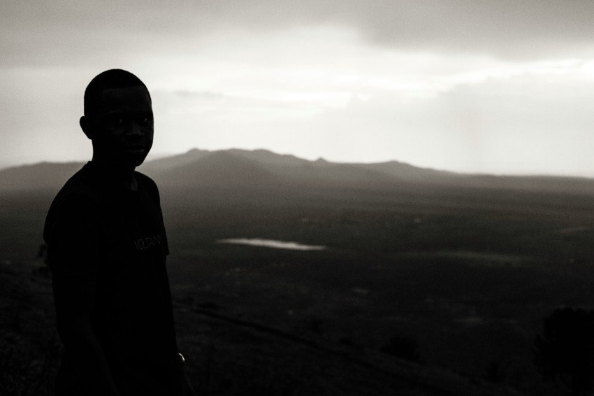 boy standing on bare hill during foggy day