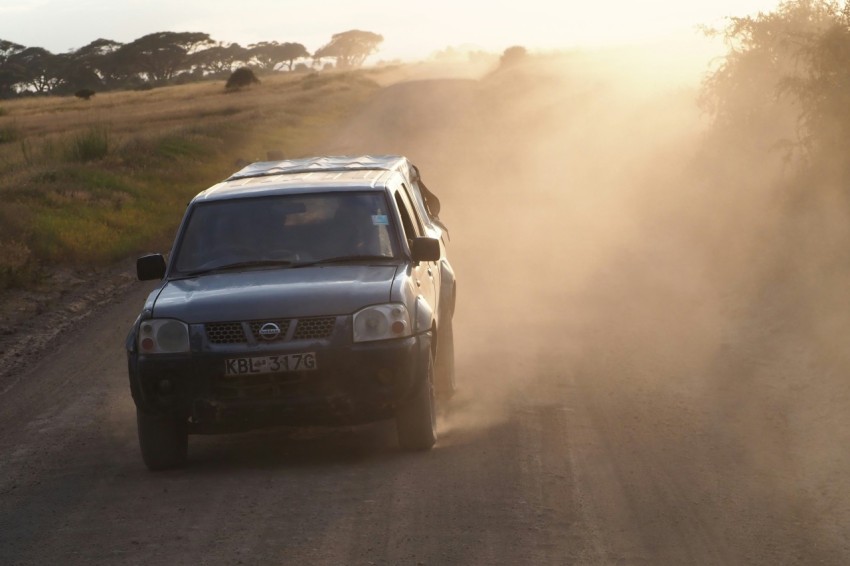 a car driving down a dirt road in the sun